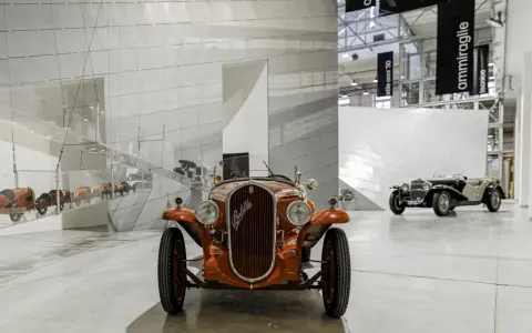 Pomarańczowy Fiat Balilla z 1933 roku na wystawie w Muzeum Fiata w Turynie. W tle inne zabytkowe samochody.
