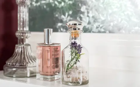Eleganckie perfumetki męskie w szklanych buteleczkach, jedna z lawendą, obok ozdobnego świecznika.