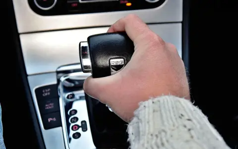 Dłoń trzymająca dźwignię zmiany biegów. Widoczny napis DSG, sugerujący skrzynię automatyczną.