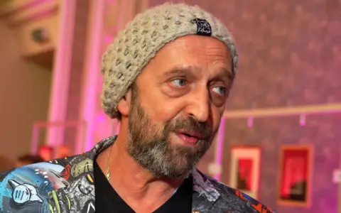 Nikodem Chabior w beżowej czapce i kolorowej kurtce, z zarostem, patrzy w bok.