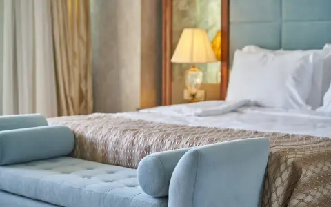 Elegancka sypialnia hotelowa z wygodnym łóżkiem i sofą. Spełnia wszelkie **hotel 4 gwiazdki wymagania** dotyczące komfortu i stylu.