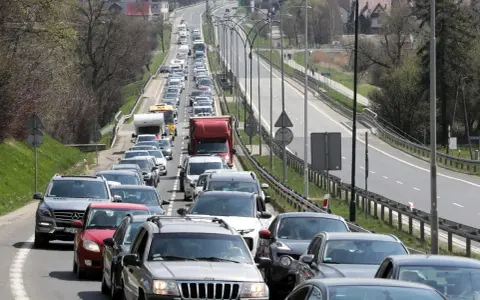 Korek na drodze, jak węzeł gordyjski, zablokował ruch. Samochody stoją w długiej kolejce, tworząc niekończący się rząd pojazdów.