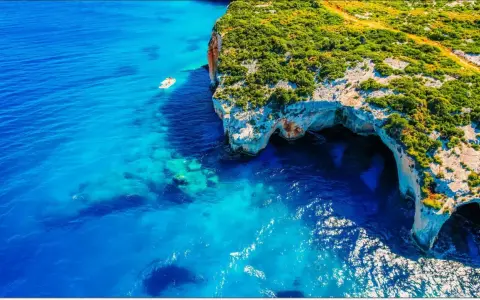 Błękitne morze i klify z jaskiniami to idealne miejsca na Zakynthos, co zobaczyć. Mała łódka kołysze się na falach.