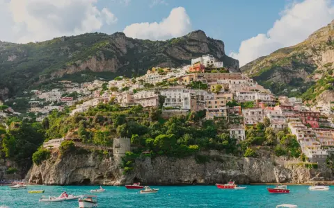 Positano, un gioiello da scoprire, perfetto per chi cerca cosa vedere a Napoli in un giorno. Case colorate aggrappate alla scogliera, mare azzurro e barche.