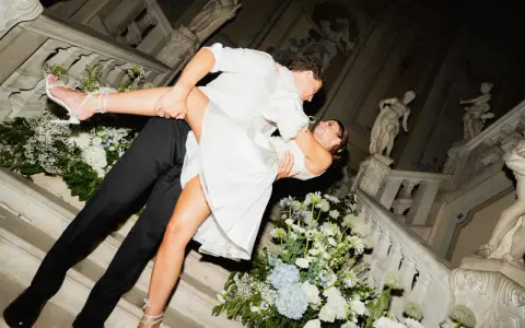 Un couple s'embrasse passionnément sur un escalier orné de fleurs, un moment clé pour réussir son mariage.