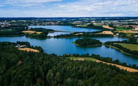 Malownicze jeziora i lasy tworzą tajemnicze miejsca na Kaszubach. Widok z lotu ptaka ukazuje spokojne wody, zielone wyspy i pola uprawne.