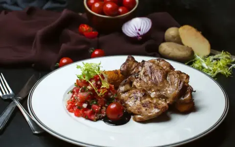 Soczysty udziec jagnięcy z salsą pomidorową i ziemniakami.