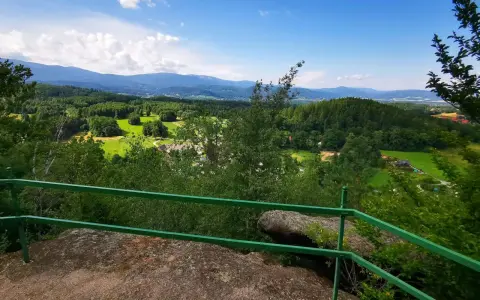 Widok z góry Witosza na zielone doliny, lasy i odległe pasmo górskie.
