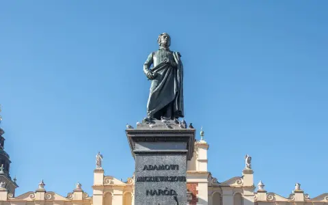 Pomnik Mickiewicza, symbol romantyczności, na tle Sukiennic. Streszczenie epoki w kamieniu i architekturze.
