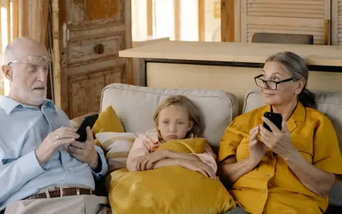 Abuela paterna celosa mira con recelo mientras el abuelo y la nieta están absortos en sus teléfonos.