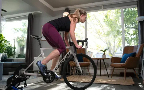 Woman training on a bike trainer in a living room. This indoor bike setup allows for a great workout at home.