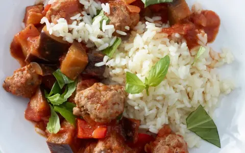 Herzhafte Salsiccia-Zubereitung in der Pfanne mit Auberginen, Paprika und Reis, garniert mit frischem Basilikum.