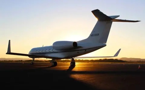 Ein weißer Privatjet steht im Sonnenuntergang auf dem Rollfeld. Verschiedene privatjets modelle sind auf dem Markt, aber dieser hier strahlt Luxus aus.