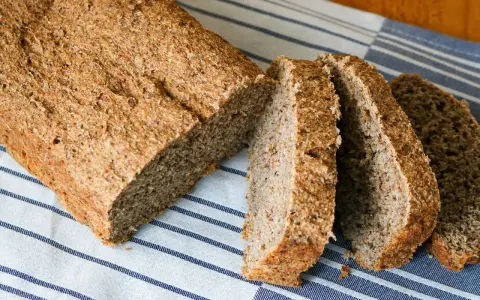 Ein frisch gebackenes vollkornbrot mit hefe, aufgeschnitten auf einem gestreiften Tuch.