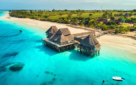 Rajskie plaże i turkusowa woda, idealne tanzania atrakcje. Domki na palach w tropikalnym otoczeniu.