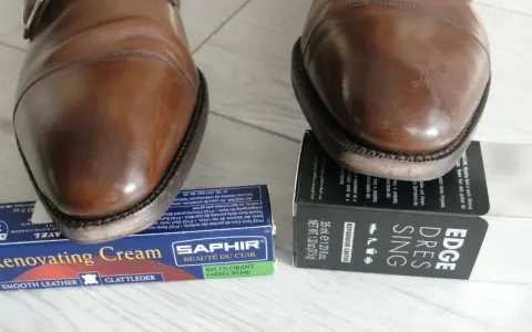 Brązowe buty męskie z klamrą, obok kremu do renowacji i preparatu do krawędzi.