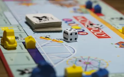 Kostka i pionki na planszy Monopoly. Gra planszowa uczy strategii, negocjacji i zarządzania finansami, realizując cele i zadania.