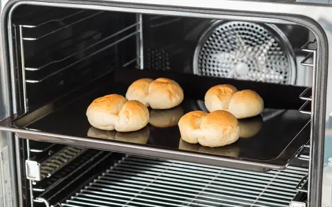 Cinq petits pains dorés sur une plaque de cuisson dans un four. C'est une bonne question : qu'est-ce qu'un lèchefrite ? C'est cette plaque !