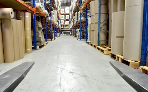 Magazyn z rolkami papieru i kartonami. Wózek widłowy gotowy do pracy, być może z systemem kod rfid do śledzenia towaru.