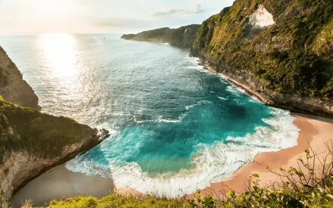 Idealne wakacje na Bali: turkusowa zatoka otoczona klifami, złoty piasek i szum fal. Raj na ziemi.