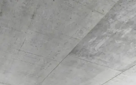 Surowy, betonowy sufit z widocznymi liniami szalunku. Betonowy sufit inspiracje dla minimalistycznych wnętrz.