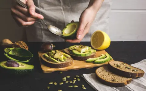 Preparazione di gustose ricette con avocado: toast con avocado, formaggio e semi.
