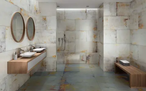Baño moderno con paredes y suelo de baldosas grises y oxidadas. Los tonos tierra y dorados de las baldosas muestran que colores combinan con el gris en un baño.