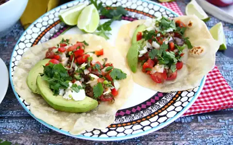 Två läckra tex mex-tacos med avokado, tomat, lök och koriander. Ett perfekt tex mex recept för en snabb och god middag.