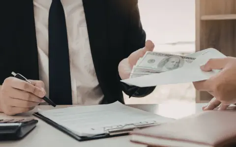 Biznesmen przekazuje kopertę z pieniędzmi, podczas gdy drugi mężczyzna podpisuje dokument. Szybka gotówka windykacja terenowa.