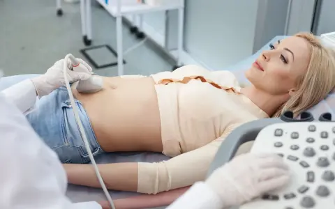 Kobieta leży na kozetce, a lekarz wykonuje jej cystografię mikcyjną, badając pęcherz moczowy.