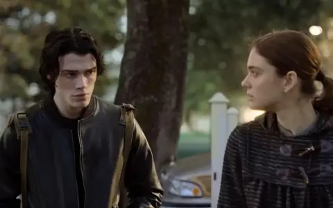 Ragazzo con giacca di pelle e ragazza con cappotto a righe, forse protagonisti di "Fabbricante di lacrime", si guardano intensamente.