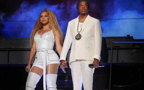 Beyoncé i Jay-Z, symbol sukcesu i majątku, na scenie w błyszczących strojach.