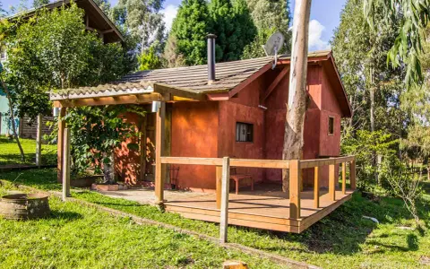 Il progetto di una piccola casa di campagna, con tetto spiovente, camino e un albero che attraversa la struttura.