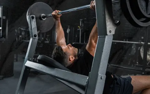Mann beim Bankdrücken, ein wichtiger Teil seines Powerlifting Trainingsplans.