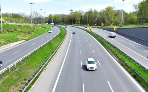 Autostrada z kilkoma samochodami i zielonymi pasami.