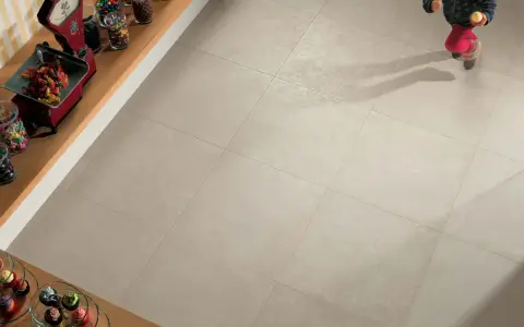 Un enfant court sur un sol carrelé 60x60. L'épaisseur du joint du carrelage est subtile, soulignant la modernité de la pose.