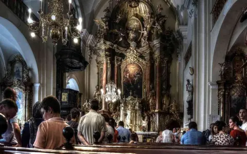 Wnętrze kościoła z bogato zdobionym ołtarzem. Ludzie siedzą w ławkach, słuchając kazania. Czy to czas na gorzkie żale?