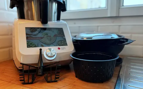 Robot culinaire Monsieur Cuisine Smart prêt à préparer une recette. Accessoires et bols empilés à côté.