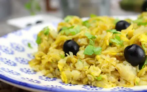 Delicioso bacalao a bras, un plato tradicional con patatas finas, huevo y aceitunas negras, adornado con perejil fresco.