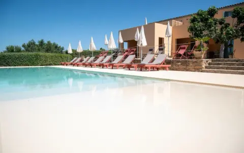 Agriturismi con piscina: lettini prendisole e ombrelloni invitano al relax in un contesto rurale.