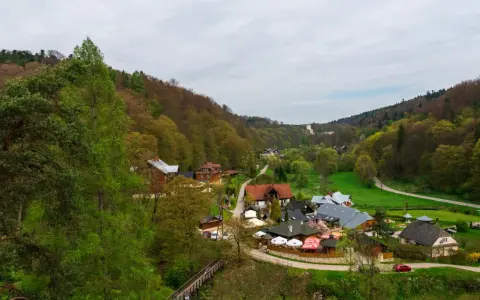 Widok na malowniczą dolinę z zabudowaniami i lasem.
