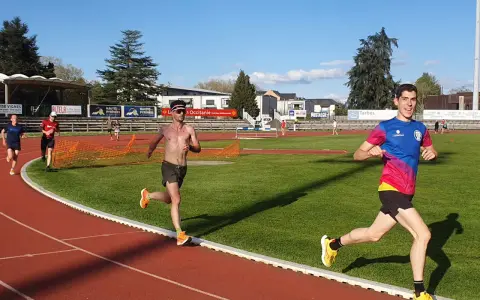 Coureurs sur piste, s'entraînant pour savoir combien de jours de repos avant une compétition. Le soleil brille sur la piste d'athlétisme.