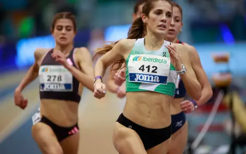 Corredoras en competición de atletismo femenino España. La atleta con el dorsal 412 lidera la carrera, mostrando su determinación.