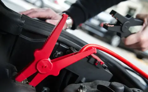 Rotes Kabel mit Krokodilklemme wird an Autobatterie angeschlossen. Plus oder Minus?