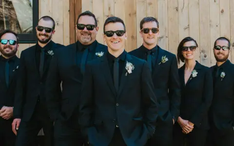 Groomsmen in matching black suits and sunglasses, showcasing stylish black suit ideas for a wedding party.