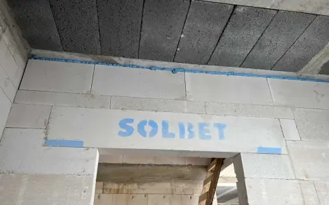 Dylatacja co to? Widoczna szczelina wypełniona pianką między betonem a bloczkami z napisem SOLBET.