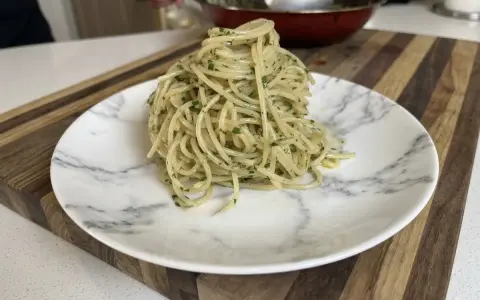 Un plato de spaghetti aglio e olio, con perejil picado, listo para disfrutar.