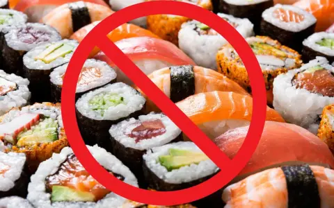 Rotes Verbotsschild über Sushi und Maki-Rollen. Achtung: verbotene Lebensmittel Schwangerschaft.