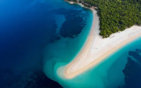 Widok z lotu ptaka na Zlatni Rat w Chorwacji. Plaże otoczone turkusowym morzem i zielonym lasem.