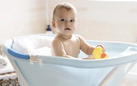Urocze dziecko w niebieskiej wanience z żółtą kaczką. Kąpiel w wanience jest świetną zabawą, a dziecko może w niej przebywać, dopóki nie zacznie samodzielnie siadać i wstawać.